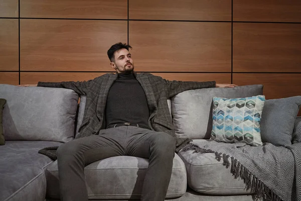 Pensiv ung man väljer ny soffa i möbelaffär — Stockfoto