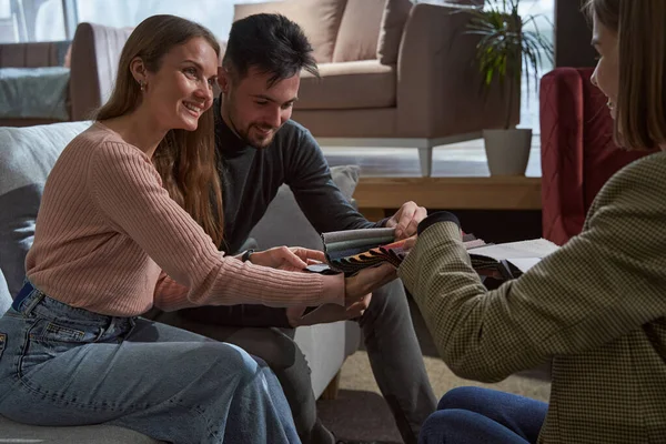Memnun müşteriler yeni kanepe için döşeme malzemesi seçiyor.