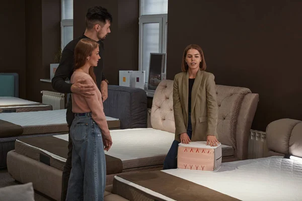 Young couple selecting new mattress in store — Stock Photo, Image