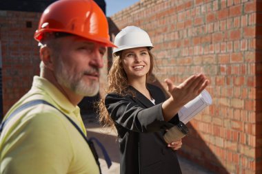 Kadın şantiye mühendisi işçilere işin kapsamını gösteriyor