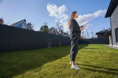 Çizimleri olan kadın mühendis özel eve bakıyor.