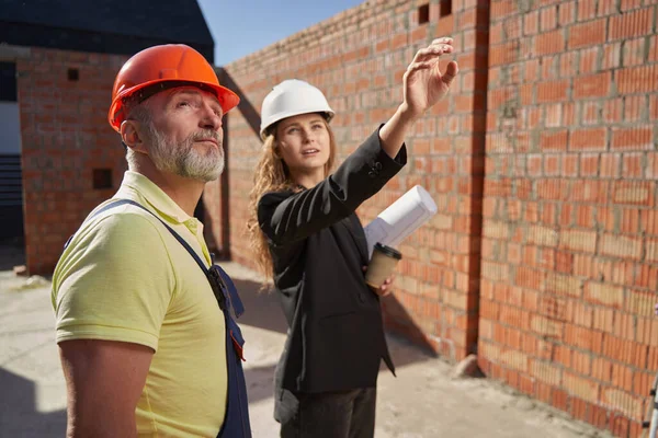 Žena popisující stavitele její nápad na stěnu domu — Stock fotografie