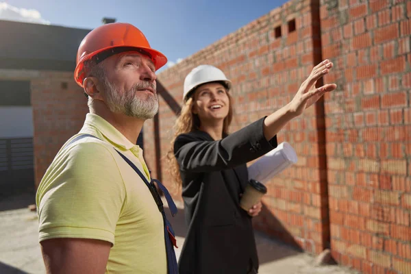 Inspired construction engineer describing building project to builder — Stockfoto