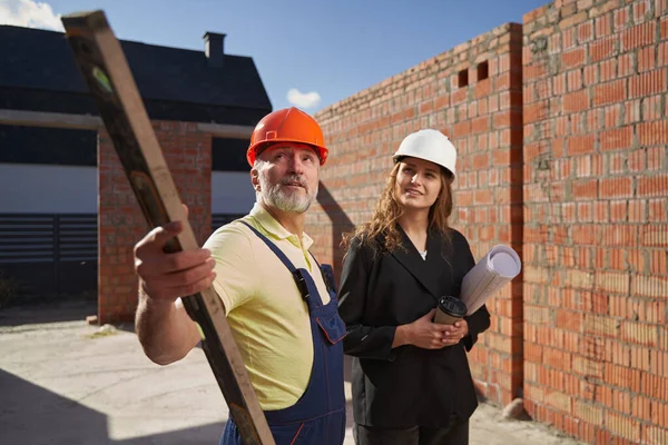 Male builder with pointing with bubble level — Stockfoto