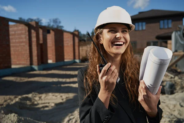 Laughing woman worker with layout talking by radio — Stockfoto