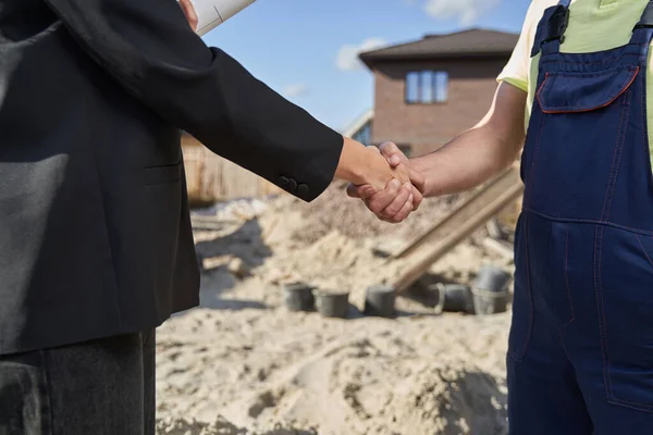 Two people shaking hands on construction area — Stockfoto