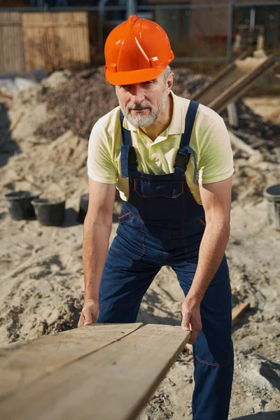 Arbetare som lägger plankan på marken vid byggnadsytan — Stockfoto