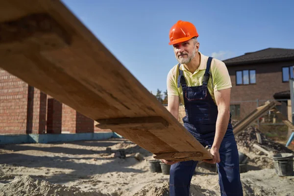 Byggnadsarbetare på väg upp med bräda — Stockfoto