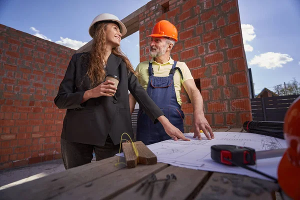 Pleased builder and woman site engineer checking drawings — Stockfoto