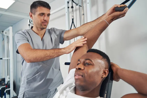 Adult man performing seated unilateral cable pull-down — Fotografia de Stock