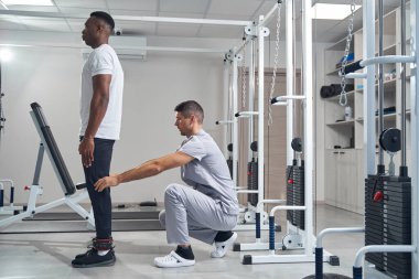 Concentrated professional kinesitherapist is examining patient legs