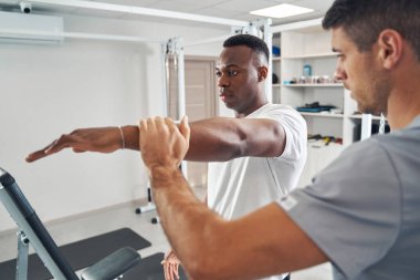 Qualified physiotherapist assessing patient upper body strength
