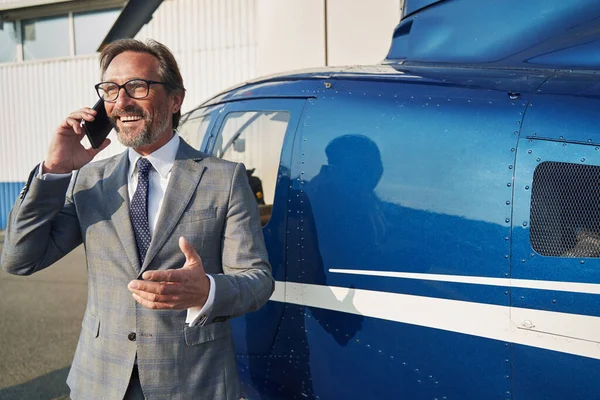 High-spirited businessman talking on his smartphone at heliport — Stok fotoğraf