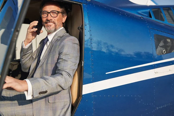 Pleased man in eyeglasses calling on smartphone in chopper — Stockfoto