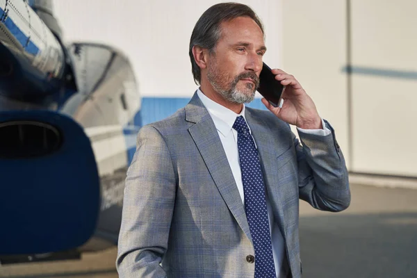 Male entrepreneur making phone call near helicopter — Stockfoto