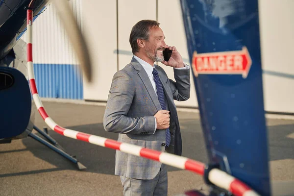 Χαρούμενος επιχειρηματίας που στέκεται στο ελικοδρόμιο κατά τη διάρκεια τηλεφωνικής συνομιλίας — Φωτογραφία Αρχείου