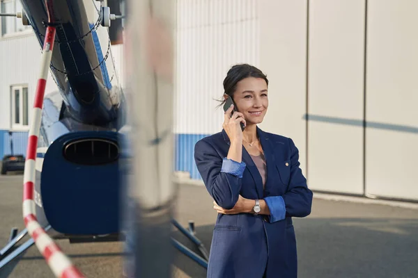 Pleased elegant woman making phone call at heliport —  Fotos de Stock