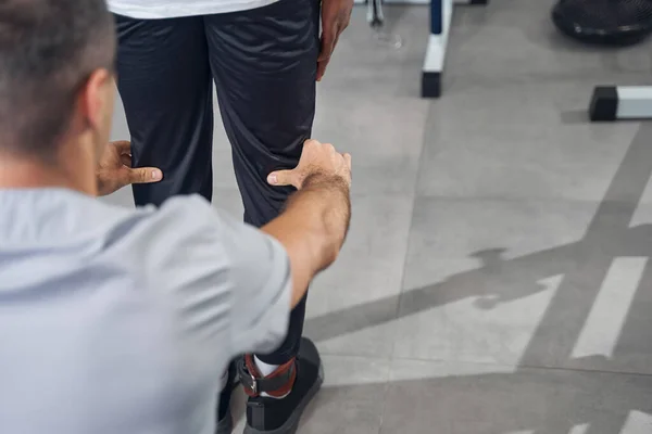 Experienced physiotherapist examining legs of man by touch — Stockfoto