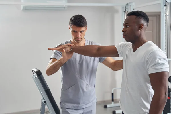 Concentrated physiotherapist performing resisted isometric test of wrist — 스톡 사진