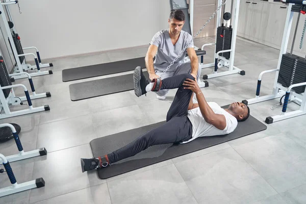 Male patient doing leg exercise using cable machine — Foto Stock