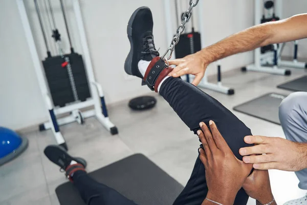 African American patient performing leg exercise using gym equipment — Foto Stock