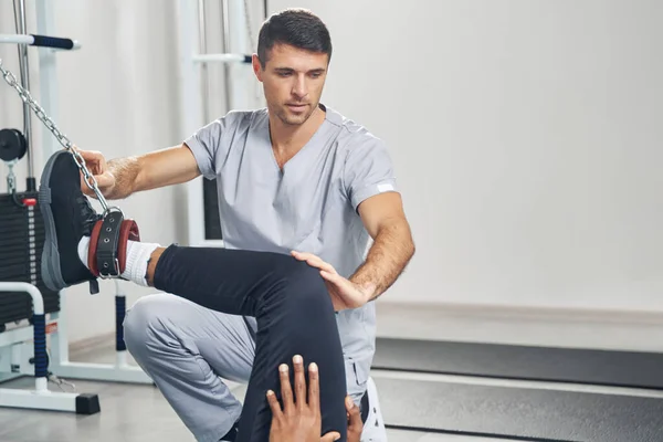 Doctor carrying out male patient leg rehabilitation — Stock Fotó