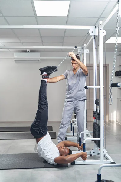 Physiotherapist employing gym equipment for patient spinal traction — Stok fotoğraf