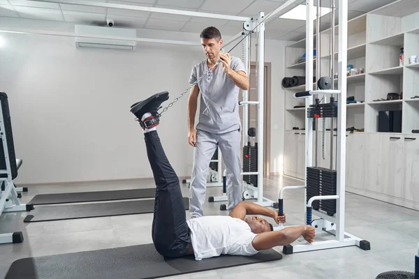 Man doing stretching exercise using gym equipment — Foto Stock