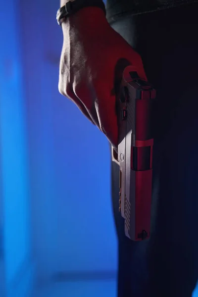 Handgun in lowered hand of male in studio — Stok fotoğraf