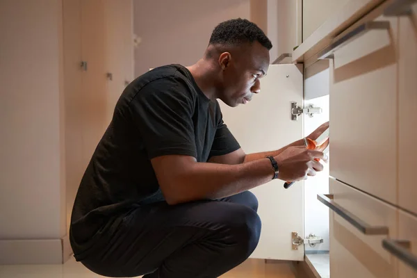 Male is repairing kitchen cupboard with pliers — Fotografia de Stock