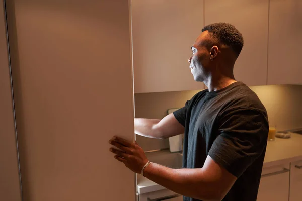 Multiracial man reaching inside kitchen cabinet with hand — Fotografia de Stock