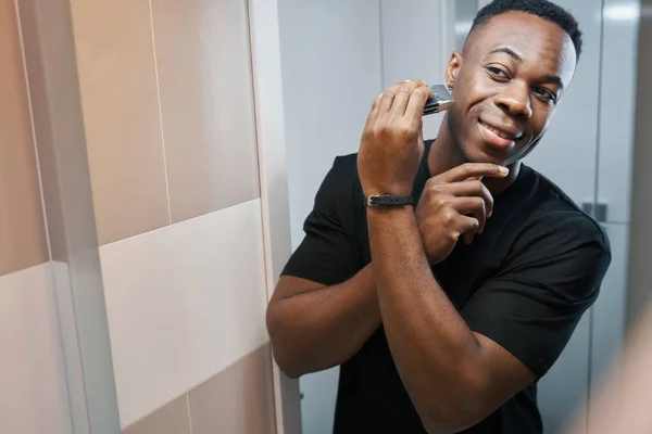 Male shaving his right cheek with electric razor — Stock fotografie