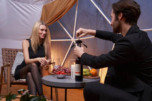 Man on a date unscrewing a bottle of wine — Stockfoto