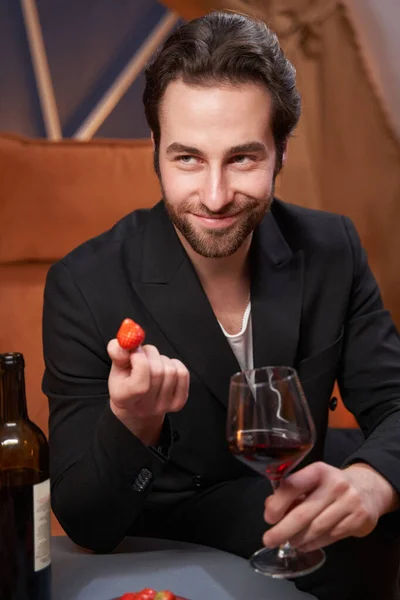 Male with wine offering strawberry to another person — Stock Photo, Image