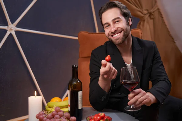 Cheerful man holding strawberry and wine with smile — Zdjęcie stockowe