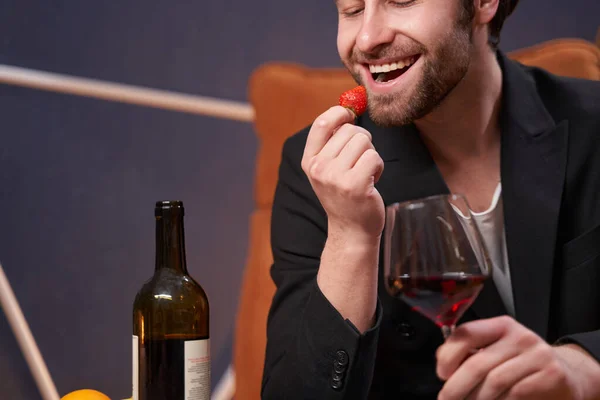Happy man taking a bite from strawberry in restaurant — Zdjęcie stockowe