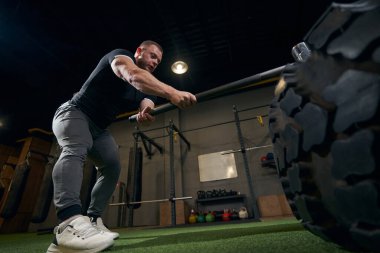 Odaklanmış ciddi vücut geliştirici lastik çarpma egzersizi yapıyor.