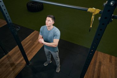 Konsantre olmuş sportif erkek barfiks çekmeye hazırlanıyor.