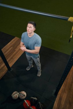 Odaklanmış beyaz adam barfiks çekmeye hazırlanıyor.