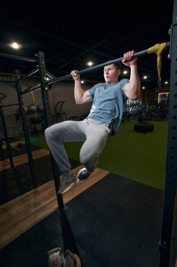 Jimnastikçi barfikste kendini yukarı çekiyor.