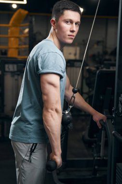 Sakin atletik adam tek kollu trisepsi itiyor.