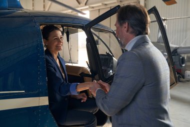 Adam, neşeli kadının helikopterden inmesine yardım ediyor.