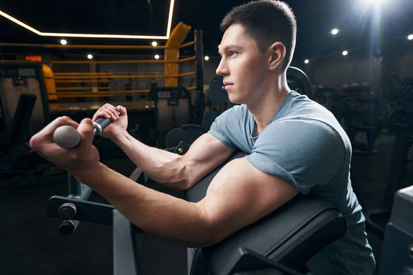 Concentrado fisiculturista fazendo exercício de parte superior do corpo em equipamentos de fitness — Fotografia de Stock