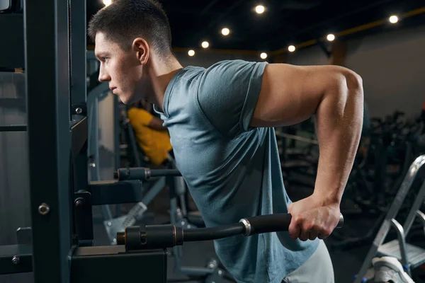 Esportista concentrado fazendo exercício de treinamento de força na máquina de fitness — Fotografia de Stock