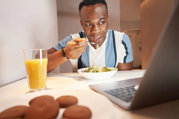 Multiracial homem está comendo refeição antes do laptop — Fotografia de Stock