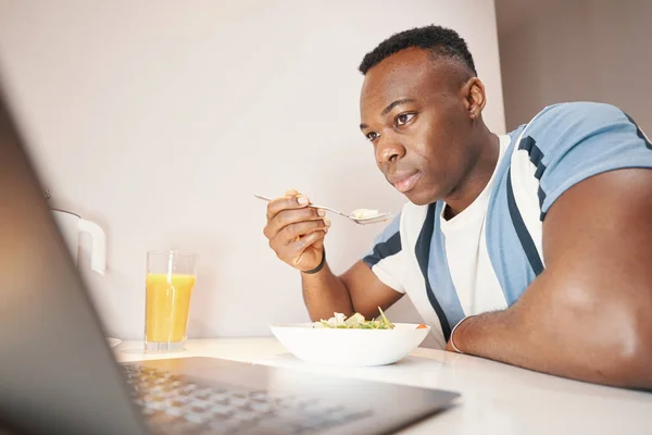 Multiracial man having meal in front of laptop — Stock Photo, Image