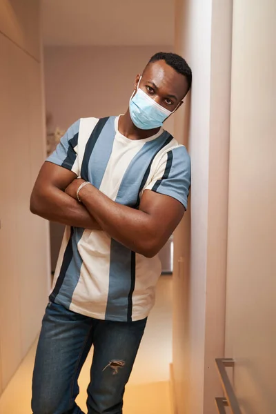 Uomo di razza mista in T-shirt e maschera in piedi nella sala della casa — Foto Stock