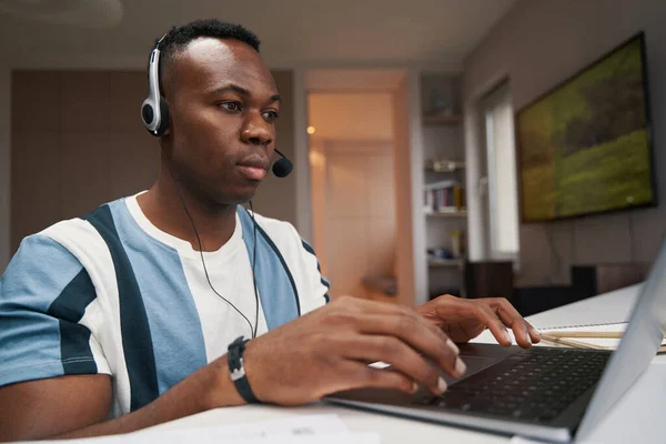 Hombre diligente trabajando en el ordenador portátil con auriculares —  Fotos de Stock