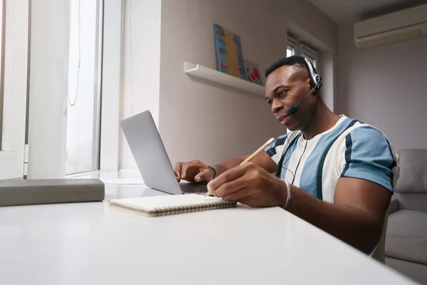 Hombre en casa trabajando en el portátil y tomando notas —  Fotos de Stock