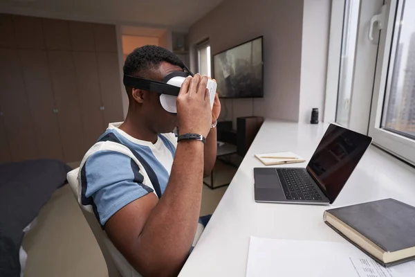 Homem colocando no fone de ouvido VR enquanto sentado antes do laptop — Fotografia de Stock